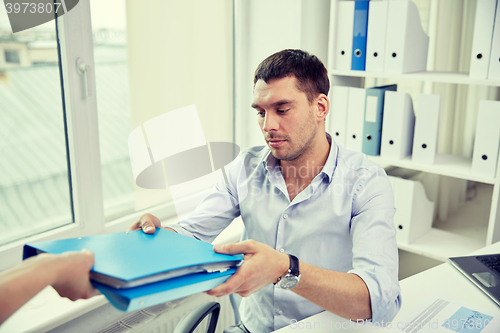 Image of businessman taking folder from secretary in office