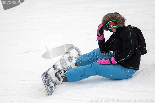 Image of Woman with snowboard rests on snow