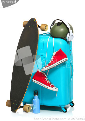 Image of The blue suitcase, sneakers, skateboard on white background.