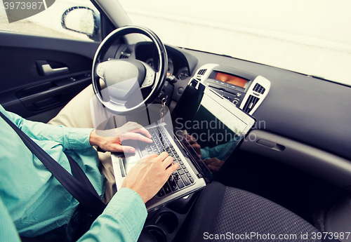 Image of close up of young man with laptop driving car