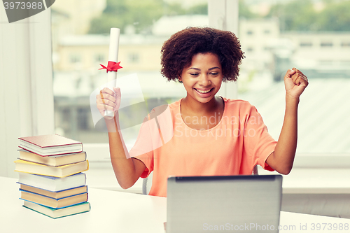 Image of happy african woman with laptop, books and diploma