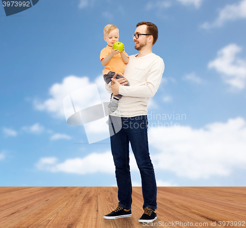 Image of happy father and little son with green apple