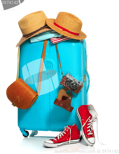 Image of The blue suitcase, sneakers, clothing, hat, and retro camera on white background.