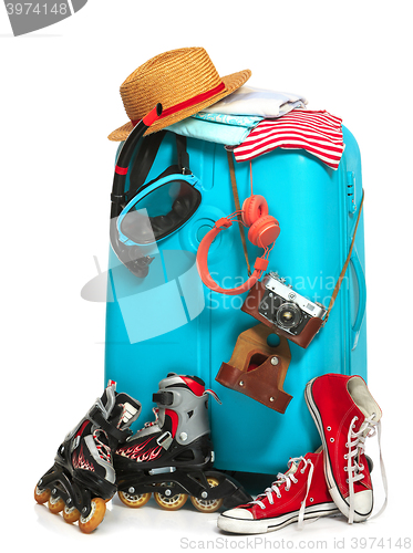 Image of The blue suitcase, sneakers, clothing, hat, and retro camera on white background.