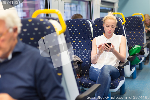 Image of Woman using mobile phone while travelling by train.