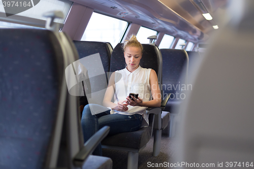 Image of Woman using mobile phone while travelling by train.