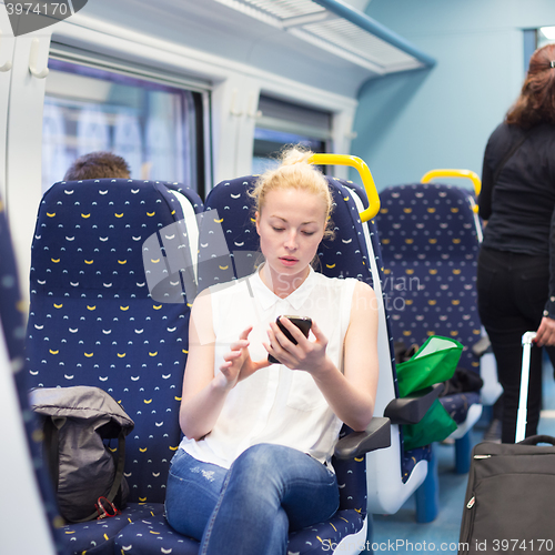 Image of Woman using mobile phone while travelling by train.