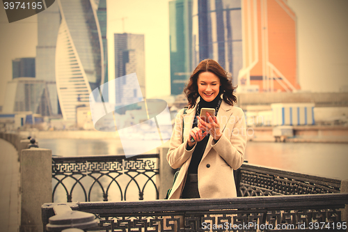 Image of smiling beautiful middle-aged woman with a smartphone