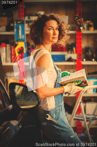 Image of woman mechanic with a wrench and repair manual in his hand