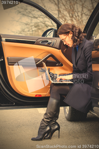 Image of Work on the road. woman in a dark coat with a laptop