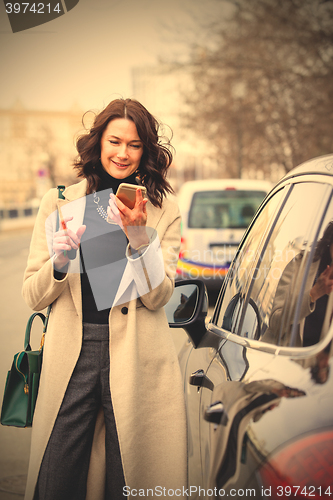 Image of smiling middle aged brunette with smartphone