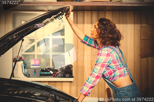 Image of beautiful woman mechanic in a garage