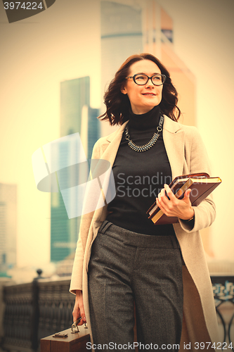 Image of brunette with a wooden case and books in their hands
