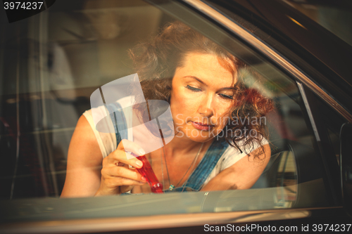 Image of emale mechanic repairing a car door with a screwdriver