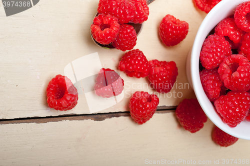 Image of bunch of fresh raspberry on a bowl and white table
