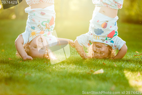 Image of The two little baby girls hanging upside down