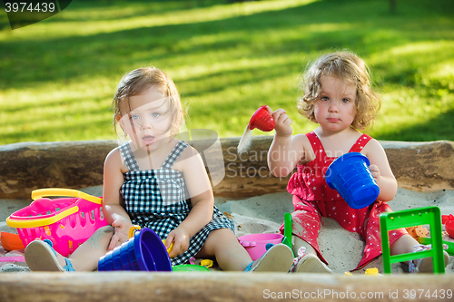 Image of The two little baby girls playing toys in sand
