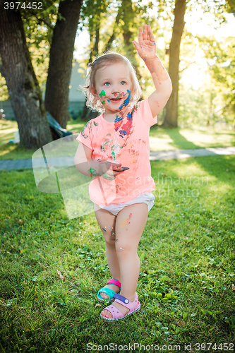 Image of Two-year old girl stained in colors against green lawn