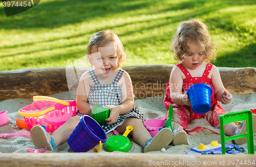 Image of The two little baby girls playing toys in sand