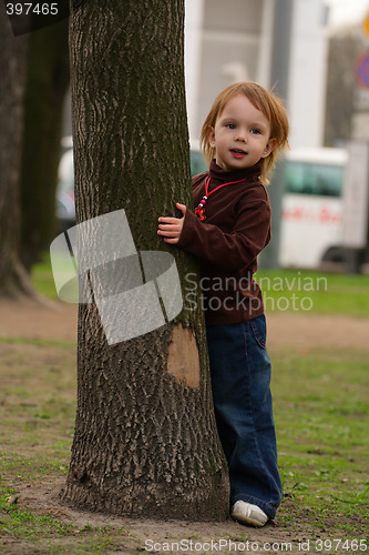 Image of Small beauty girl playing hide-and-seek at the park.