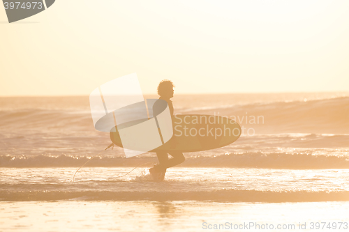 Image of Silhouette of surfer on beach with surfboard.