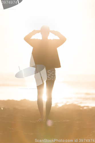 Image of Woman on sandy beach watching sunset.