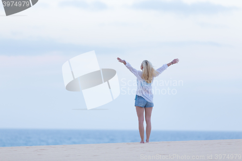 Image of Free woman enjoying freedom on beach at dusk.