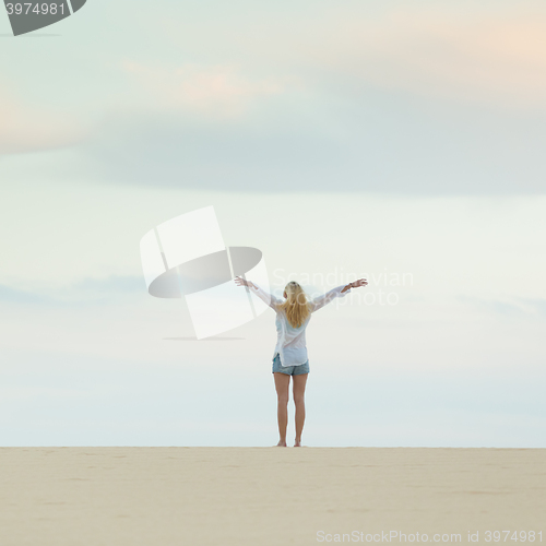 Image of Free woman enjoying freedom on beach at dusk.