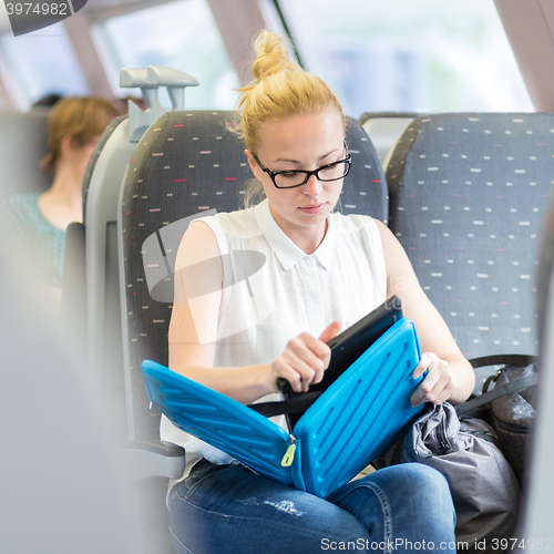 Image of Woman travelling by train working on laptop.
