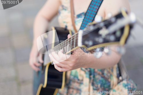 Image of Female street musician playing guitar.