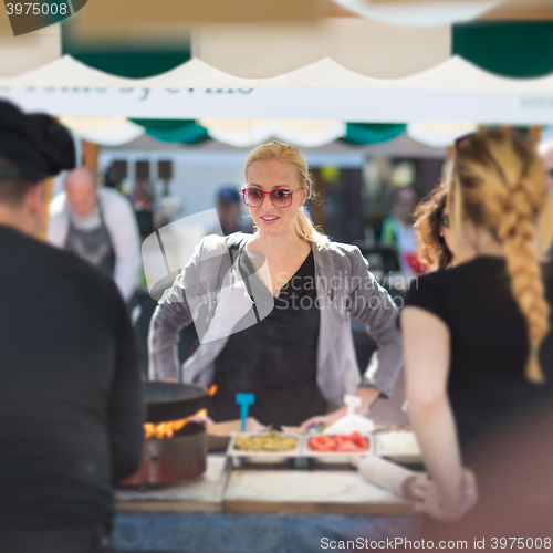 Image of Woman buying meal at street food festival.