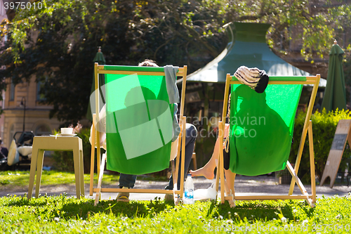 Image of Silhouette of relaxed couple on deckchairs in a park