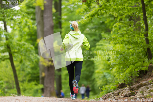 Image of Sporty young female runner in the forest. 