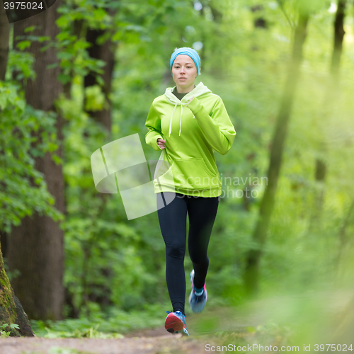 Image of Sporty young female runner in the forest. 