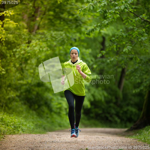 Image of Sporty young female runner in the forest. 