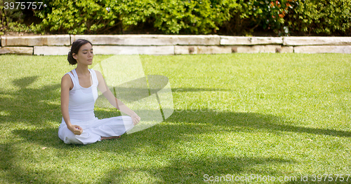 Image of Lovely young woman meditating in the garden