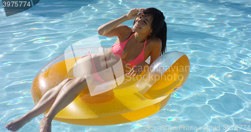 Image of Sexy young woman sunbathing in a swimming pool