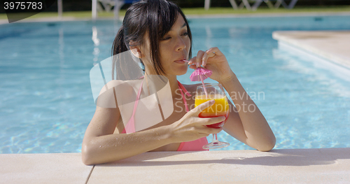 Image of Pretty young woman sipping a cocktail in  pool