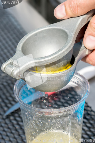 Image of manual metal juicer lemon in a plastic Cup