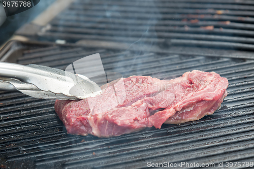 Image of raw steak with spices on metal grill