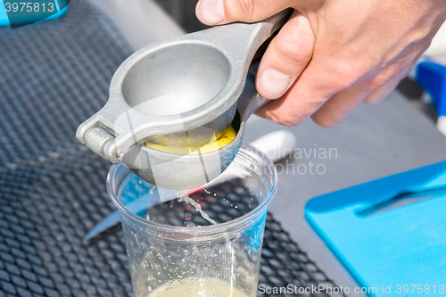 Image of manual metal juicer lemon in a plastic Cup