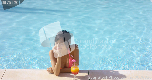 Image of Contented woman at pool edge with drink