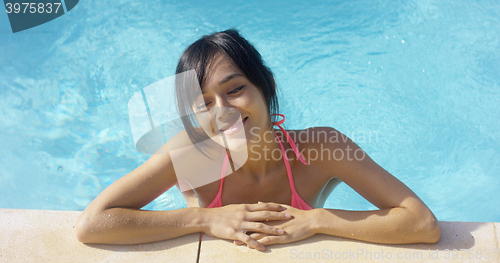 Image of Woman in pink swim suit smiles to herself
