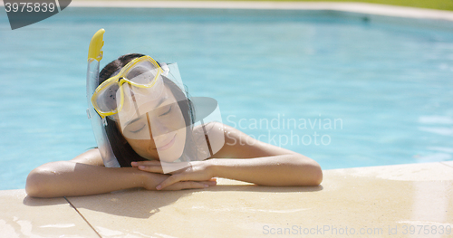 Image of Woman in snorkel and goggles rests by pool