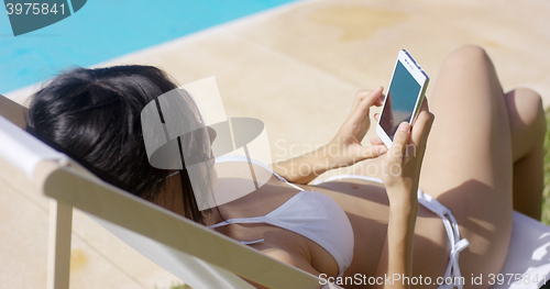 Image of Young woman browsing on a mobile in the summer sun