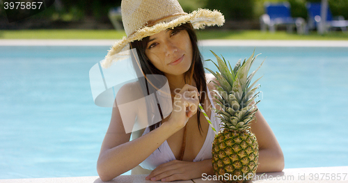 Image of Sunbathing beauty drinks from a pineapple
