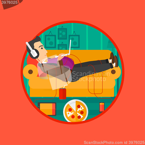 Image of Man lying on sofa with many gadgets.