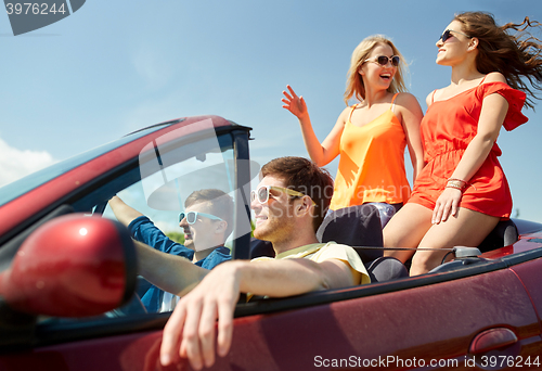 Image of happy friends driving in cabriolet car
