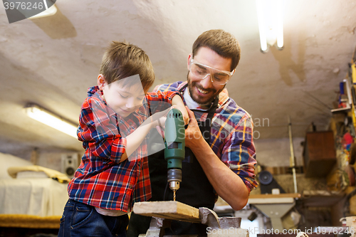 Image of father and son with drill working at workshop