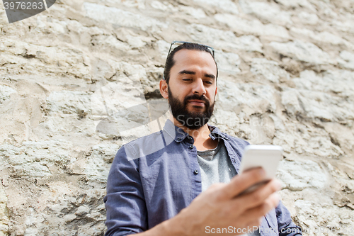 Image of man texting message on smartphone at stone wall